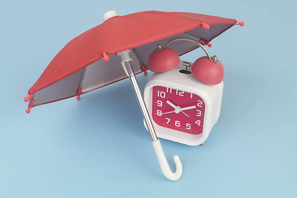 istock Alarm clock under umbrella on blue background. 2232469459