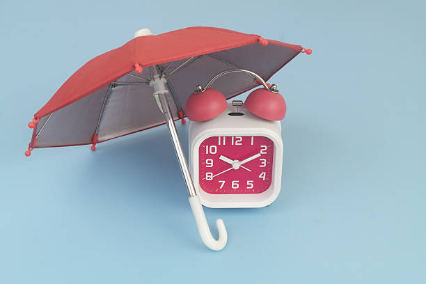 istock Alarm clock under umbrella on blue background. 2232469469