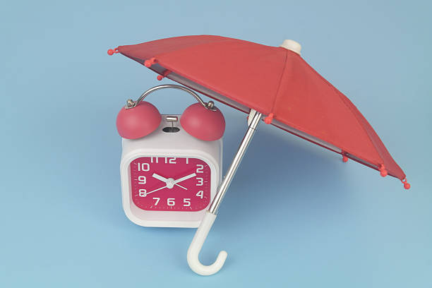 istock Alarm clock under umbrella on blue background. 2232469474