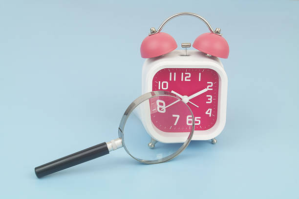 istock Alarm clock under magnifying glass on blue 2232469484