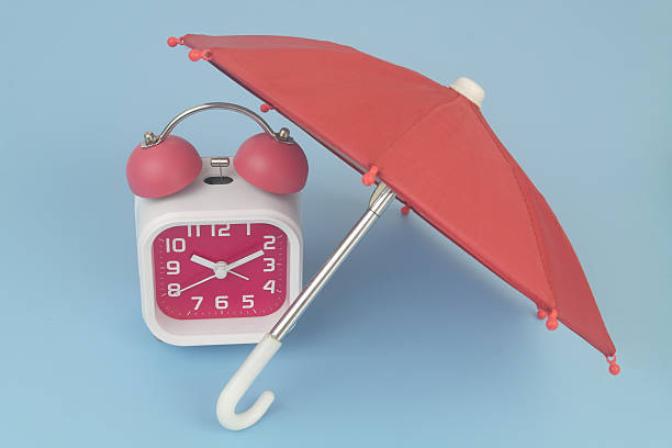 istock Alarm clock under umbrella on blue background. 2232469496