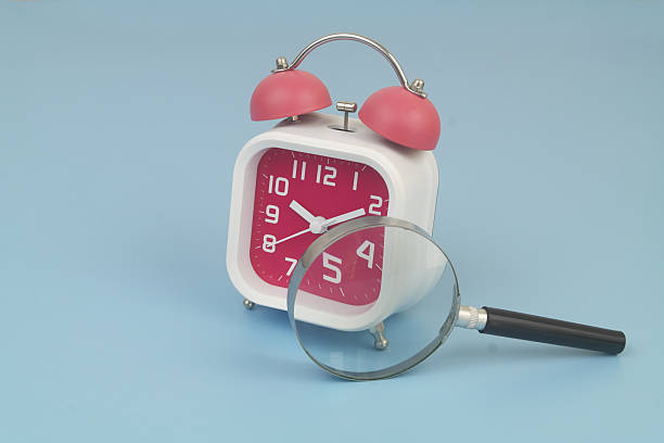 istock Alarm clock under magnifying glass on blue 2232469504