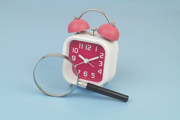 istock Alarm clock under magnifying glass on blue 2232469513