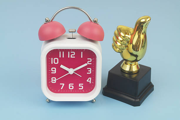 Thumbs up and alarm clock on blue background.