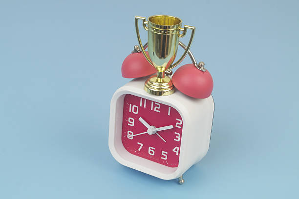 Gold champion cup and alarm clock on blue background. Sport events time concept.