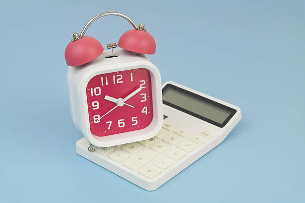 istock Alarm clock on calculator on blue background. 2232469897