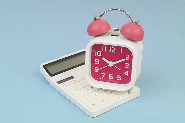 istock Alarm clock on calculator on blue background. 2232469898