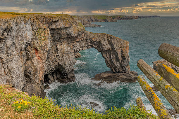 The Green Bridge of Wales is a natural arch formed from Carboniferous Limestone within the Pembrokeshire Coast National Park, Pembrokeshire, Wales. It is located in the Castlemartin military training area just beyond the car park at Stack Rocks.  Castlemartin, Pembrokeshire, United Kingdom
