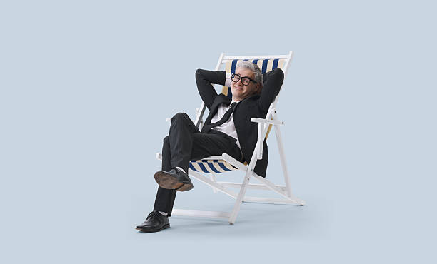 istock Manager in a black suit relaxing while sitting on a beach chair, isolated on a neutral background. 2232470612