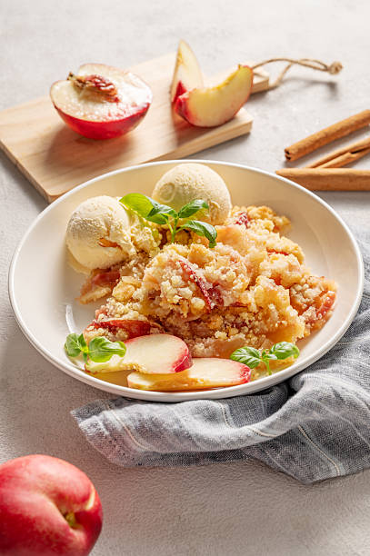 istock Peach crumble or cobbler with vanilla ice cream scoops and cinnamon on a plate on a light background 2232470683