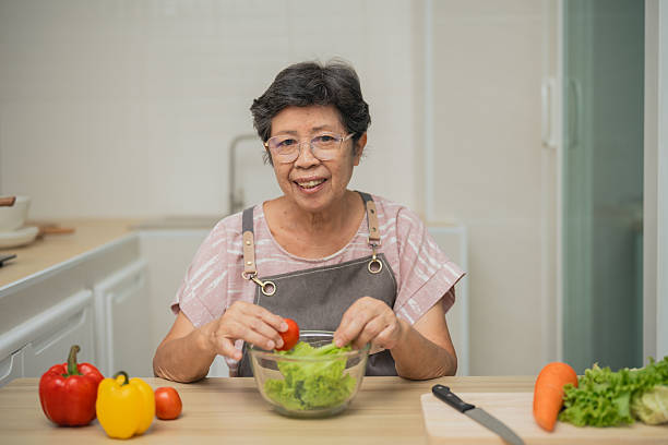 istock Senior woman preparing fresh salad with tomatoes and lettuce in a bright kitchen setting, healthy cooking and nutrition concept, home lifestyle 2232472552