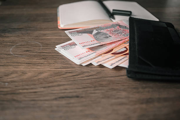 istock Cambodian Riel banknotes inside a wallet with a notebook and pen on a wooden table. 2232474880