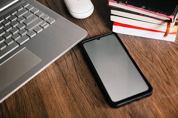 istock Smartphone with blank screen next to a laptop and mouse. 2232475088