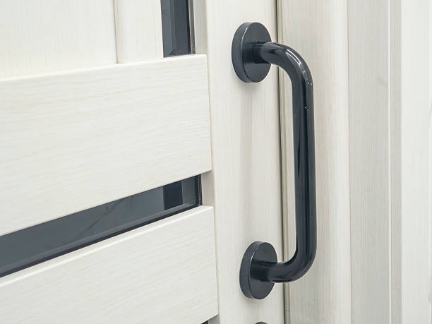 istock Black metallic door handle gripping white wooden panel with glass inserts, emphasizing minimalist architectural detail and contemporary interior styling 2232475881