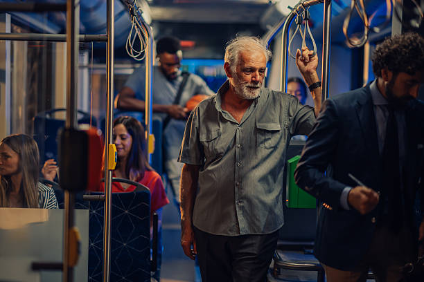 istock Senior man holding handrail while standing on a moving bus at night 2232478041