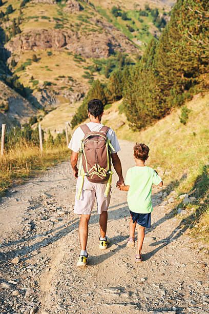 istock Father holding son's hand while walking together on a rocky mountain trail, exploring nature and enjoying outdoor family adventure 2232479766