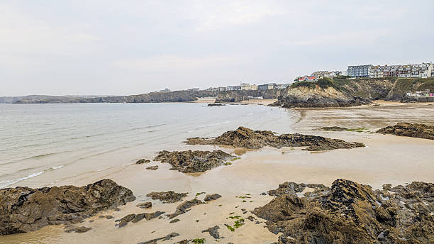 istock Coastal beach scene showcasing a sandy shore, rocks, and a seaside town under a cloudy sky. 2232480767