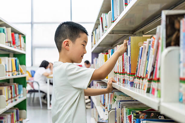 istock Young boy selecting books from library shelves 2232481446