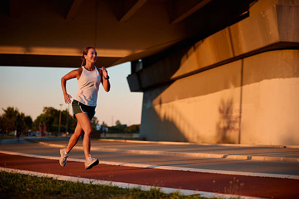 istock Young sportswoman running under a bridge at sunset 2232481951