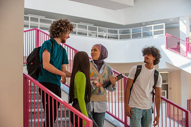 istock A group of happy diverse college students hanging out they are talking with each other while walking in the university hallway. 2232485920