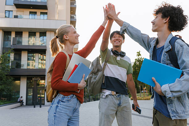 istock Three students smiling and high-fiving outdoors at a campus 2232487329