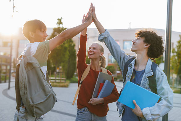 istock Group of happy students high-fiving outdoors in a campus setting 2232487704