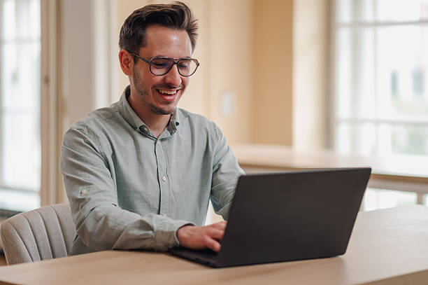 istock Young businessman working from home, typing on laptop and smiling 2232487773