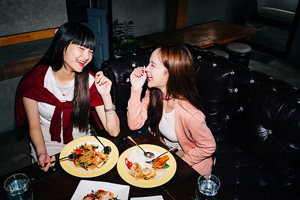 Laughing young women dining on spaghetti together