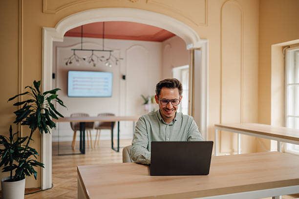 istock Young businessman smiling and working on laptop in modern office 2232488115