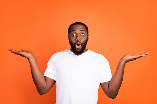 istock Portrait of attractive amazed guy holding on palms copy empty space isolated over bright orange color background 2232488565
