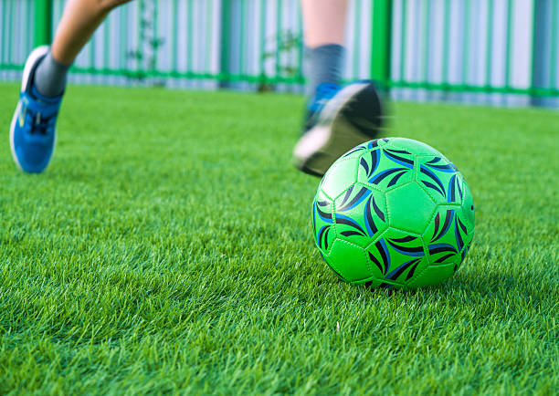 Football player foot with ball on artificial turf surface