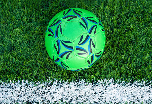 Soccer ball on artificial green grass field with white line marking