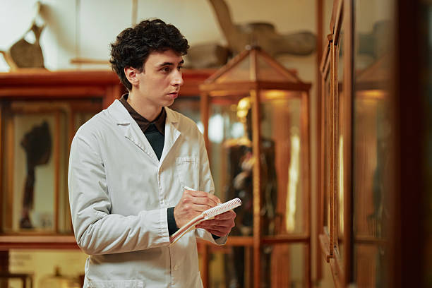 istock Young Adult Caucasian Man Observing Exhibit While Taking Notes in Museum 2232493275