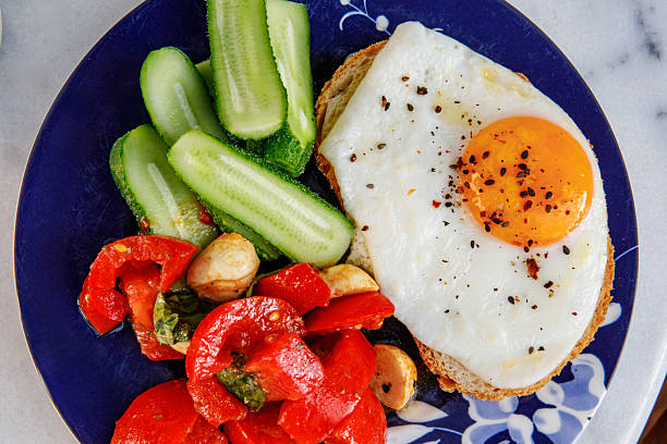 Healthy breakfast with fried egg, cucumber, fresh tomatoes and herbs. Nutritious morning meal with natural ingredients