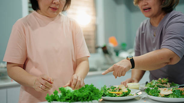 istock Two joyful elderly women preparing fresh salads together in the kitchen for dinner 2232496110