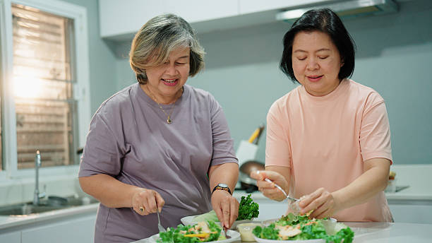 istock Two joyful elderly women preparing fresh salads together in the kitchen for dinner 2232496119