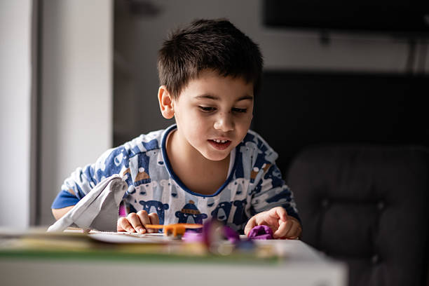istock Cute boy playing with modeling clay at home 2232496579