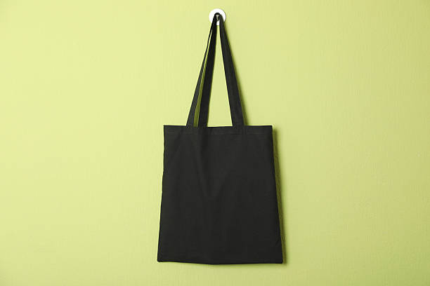 Black eco bag hanging on green wall. Mockup for design