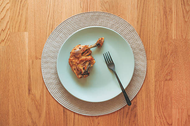 Grilled chicken drumstick served on a plate with fork, top view. Copy space included.