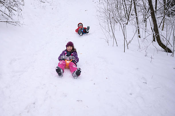 istock Happy children sliding down snowy hill in winter forest 2232497389