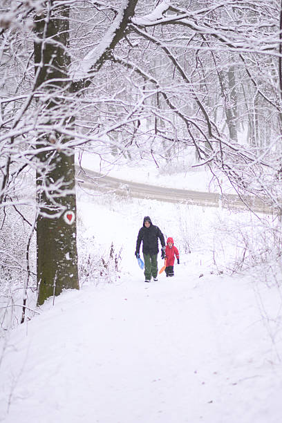 istock Father and son walking down snowy path in winter forest 2232498185