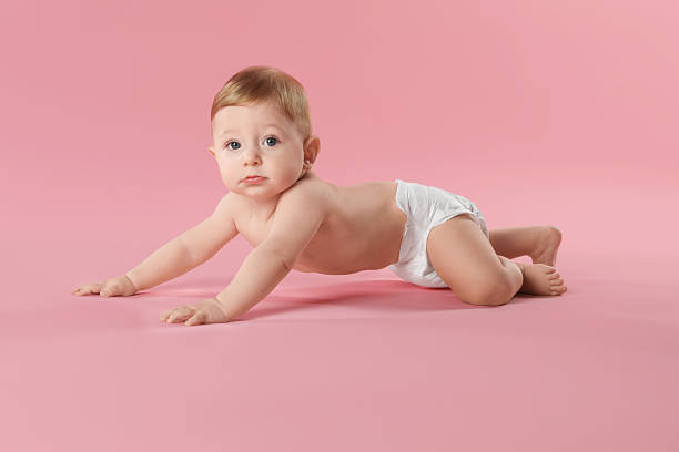 istock Cute little baby in diaper crawling on pink background 2232498795