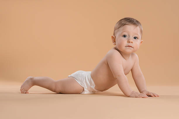 istock Cute little baby in diaper crawling on beige background 2232498869