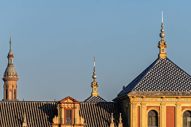 One of the towers of the Plaza de España emerges behind the tiled rooftops of the Palacio de San Telmo