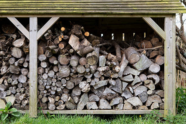A background of many logs of eucalyptus trees stacked in rows in a warehouse with stiles and a galvanized roof for retail sale in rural Thailand.