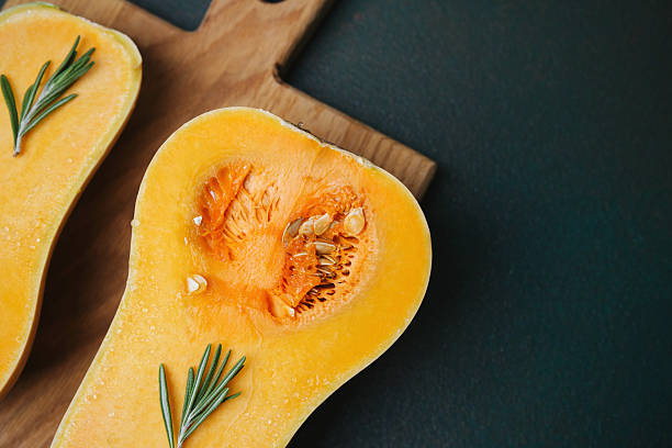 istock Butternut squash halves with fresh rosemary sprigs on a rustic wooden board. 2232503802