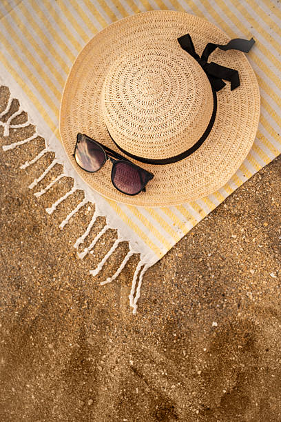 istock Straw hat and sunglasses resting on striped towel on sandy beach 2232504074