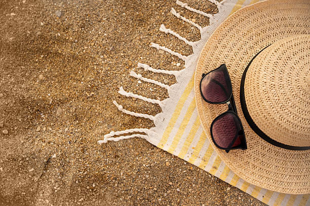 istock Straw hat and sunglasses lying on beach towel on sand 2232504111