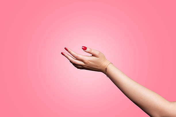 istock A young woman's hand reaching out to accept something with a cupped hand on a pink background 2232509461