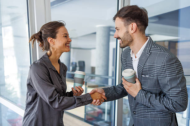 istock Business people shaking hands while holding coffee cups 2232516188